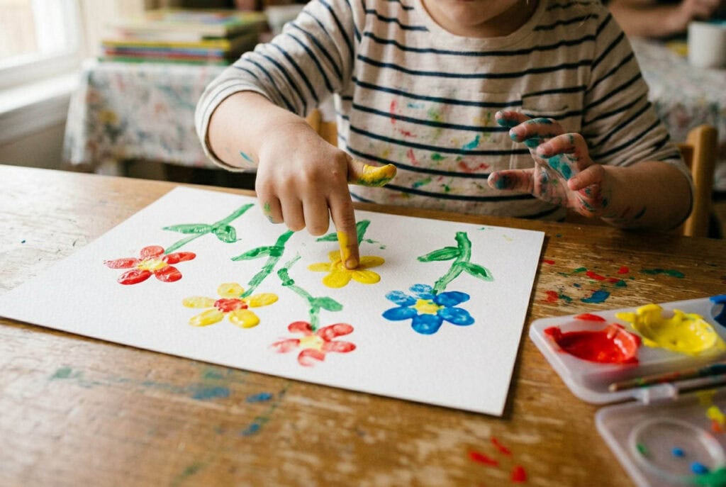 Fünfjähriges Kind macht Blumen mit Fingerabdrücken aus Farbe